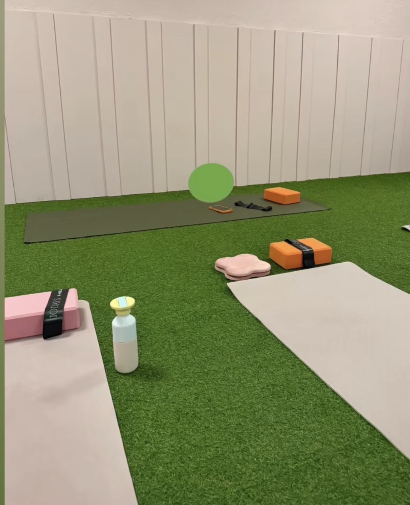 Pilatesmatten, blokken en kussens klaar voor de les op het kunstgras