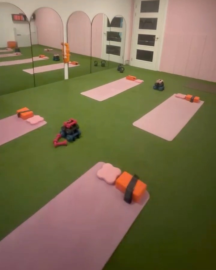 De studio met de roze boogspiegels, matten en kettlebells klaar op het kunstgras